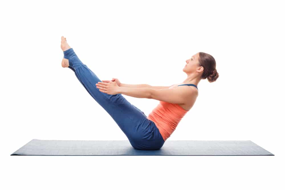 Woman practices yoga asana Paripurna navasana