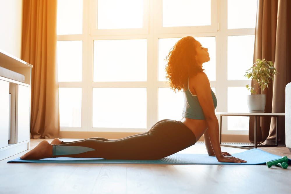 A pretty black girl doing yoga on a thin yoga mat