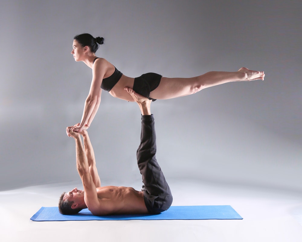 Man and women doing a yoga pose for two people